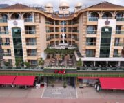 TAÇ Premier Hotel & Spa Alanya’nın palmiyelerle çevrili açık yüzme havuzu ve şezlong alanı.