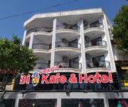 “Karikatur Bi Hotel & Cafe’nin grafiti duvar sanatıyla süslenmiş cephesi ve modern oturma alanları.”