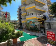 Alanya Queen Apart Otel’in dış cephesi, balkonlu odaları ve giriş alanıyla birlikte gün ışığında görüntülenmiş.