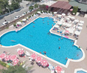 Club Sidar Apart Otel’in geniş açık yüzme havuzu, apart blokları ve şezlonglarla çevrili dinlenme alanı güneşli bir yaz gününde görüntülenmiş