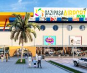 Gazipaşa Airport AVM giriş cephesi; modern mimari, geniş yürüyüş alanı, mağaza vitrinleri ve havalimanı ulaşım noktalarına yakın alışveriş merkezi görünümü Alanya