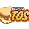Alanya Tost’ta sunulan üç katlı karışık tost; bol kaşar, sucuk, domates ve biber eşliğinde servis edilen tost tabağı ve yanında ayran
