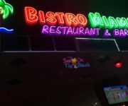 Bıstro Miami Restaurant & Bar Alanya’da şık dış mekân masasında kokteyller, mezeler ve Akdeniz esintili ana yemekler yer alıyor; arka planda palmiye ağaçları ve aydınlatılmış bahçe dekorları dikkat çekiyor.