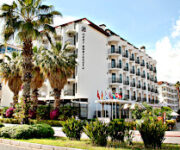 Otel Boulevard Alanya’nın palmiye ağaçlarıyla çevrili dış cephesi ve açık yüzme havuzu