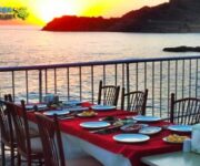 Giritli Balık Evi'nde deniz manzaralı masada servis edilen ızgara levrek, mezeler ve zeytinyağlılar. alanya