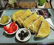 Tostçu Servet Alanya’da çıtır ekmekli, bol kaşarlı tost ve yanında servis edilen patates kızartması ve ayran sunumu