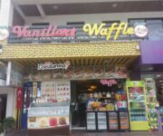 Alanya’da hizmet veren Vanillart Waffle & Cafe’nin dış cephesi ve renkli waffle sunumlarıyla süslenmiş masa görüntüsü