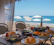 Alanya’da denize sıfır konumda yer alan Rest in Beach Plaj №54'te şezlonglar, güneş şemsiyeleri ve masmavi Akdeniz manzarası