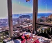 Manzara Restaurant Alanya’da şık bir masa düzeninde, şehir ve deniz panoraması eşliğinde sunulan zengin bir kahvaltı/akşam yemeği sofrası.