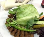 Komagene Güllerpınarı Alanya şubesinde servis edilen bol yeşillikli etsiz çiğköfte dürüm tabağı