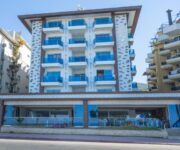 “Kleopatra Life Hotel’in plaja birkaç adım mesafedeki cephesi, balkonlu odaları ve açık yüzme havuzu.”