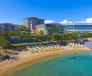 Alanya’da denize sıfır konumda yer alan Land Of Paradise Beach Hotel’in havuz başı ve modern bina görüntüsü