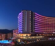 Diamond Resort SPA Hotel Alanya’nın palmiyelerle çevrili havuzu ve modern mimariye sahip otel binası.