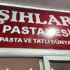 Şıhlar Pastanesi’nin vitrininde sergilenen renkli yaş pastalar, taze kurabiyeler ve geleneksel Türk tatlılarıyla dolu tezgâh gün ışığında görüntülenmiş