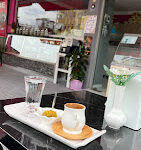 Papatyam Cafe’nin çiçeklerle süslenmiş açık oturma alanı, renkli dekorasyonu ve servis edilen kahve & tatlı tabaklarıyla birlikte gün ışığında görüntülenmiş