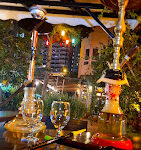 Premier Grand Cru Restaurant Saklı Bahçe’de yemyeşil ağaçların gölgesinde, şık bir masa düzeninde servis edilen gurme akşam yemeği tabağı ve şarap