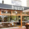 Buzzy Mahmutlar’da modern cafe ve bar alanı, masalarda içecekler ve rahat oturma alanlarıyla misafirlerin keyifli vakit geçirdiği ortam.