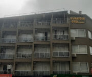 Günaydın Otel Alanya’nın giriş cephesi, palmiyelerle çevrili açık alanı ve modern tasarımıyla güneşli bir günde görüntülenmiş