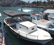 Alanya kıyısında demirli, 2006 yapımı sahibinden satılık ahşap gövdeli ve pancar motorlu özel tekne, güneşli bir günde görüntülenmiş.