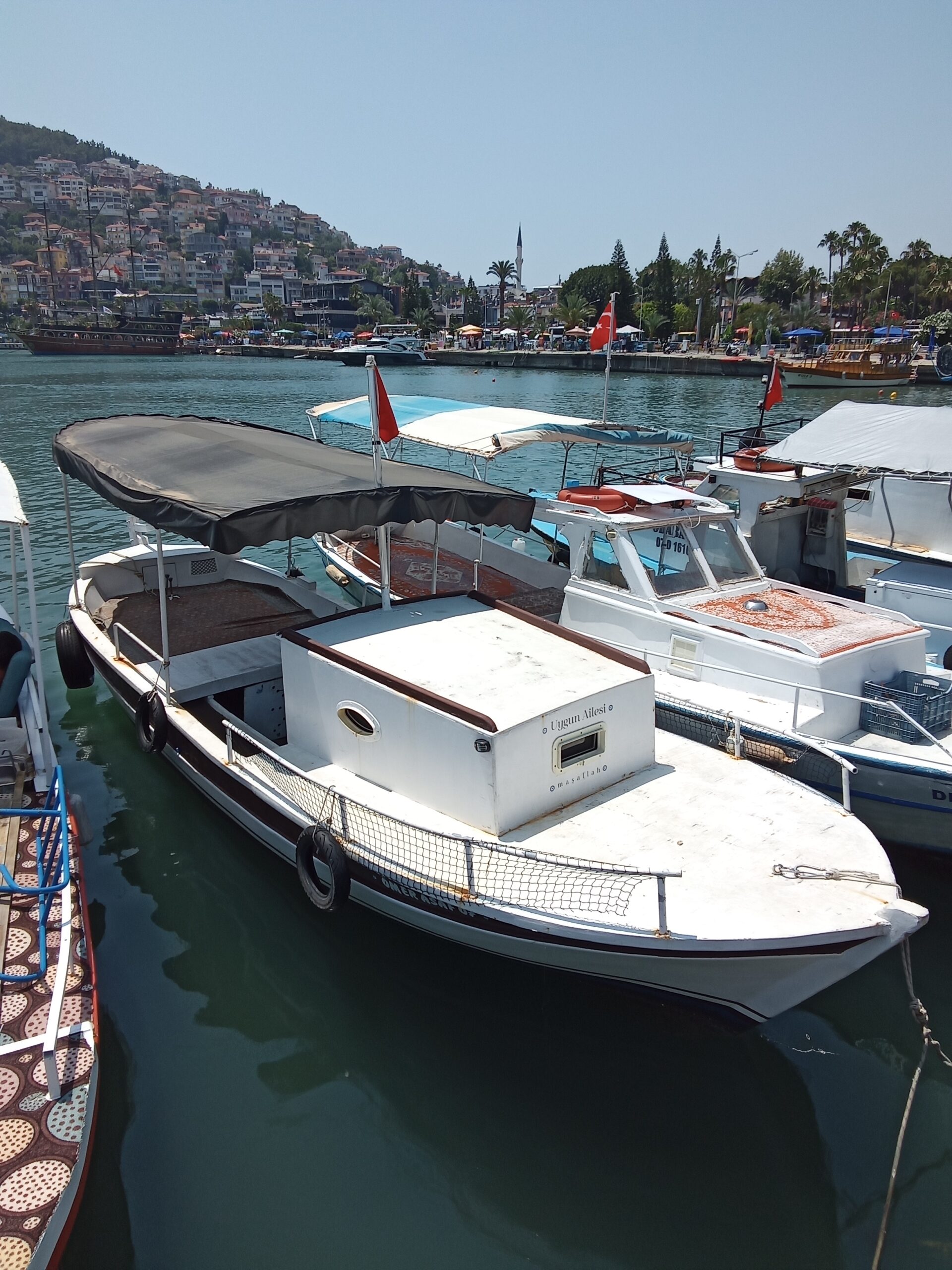 Alanya kıyısında demirli, 2006 yapımı sahibinden satılık ahşap gövdeli ve pancar motorlu özel tekne, güneşli bir günde görüntülenmiş.