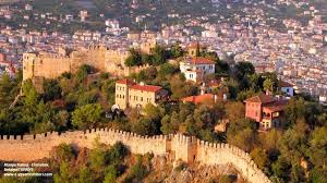 “Antik limanın önünden geçen tekneler ve arka planda yükselen modern Alanya binaları.”