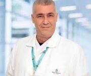 “Dr. Hikmet Yaşbala modern muayene odasında hastalarına profesyonel tıbbi hizmet sunarken.”