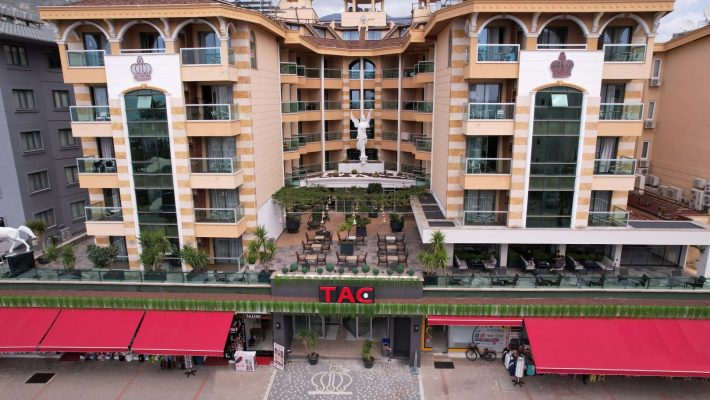 TAÇ Premier Hotel & Spa Alanya’nın palmiyelerle çevrili açık yüzme havuzu ve şezlong alanı.