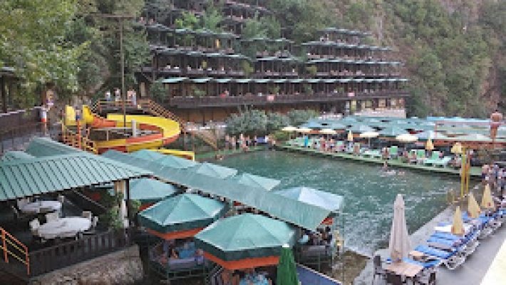 Alanya Dimçayı’nda doğal çam ormanlarının içinde akan berrak nehir; üzerindeki restoran salıncakları, serinletici sular ve doğayla iç içe masalarla birlikte görüntülenmiş