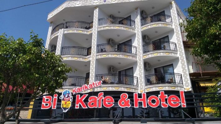 “Karikatur Bi Hotel & Cafe’nin grafiti duvar sanatıyla süslenmiş cephesi ve modern oturma alanları.”