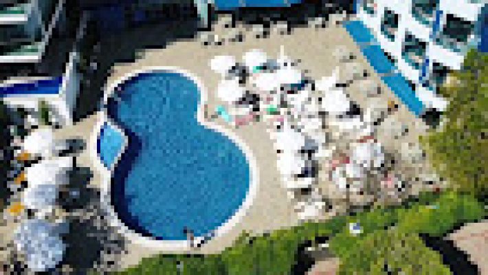 Grand Zaman Garden Hotel’in geniş havuz alanı ve modern mimariye sahip otel binası, Alanya