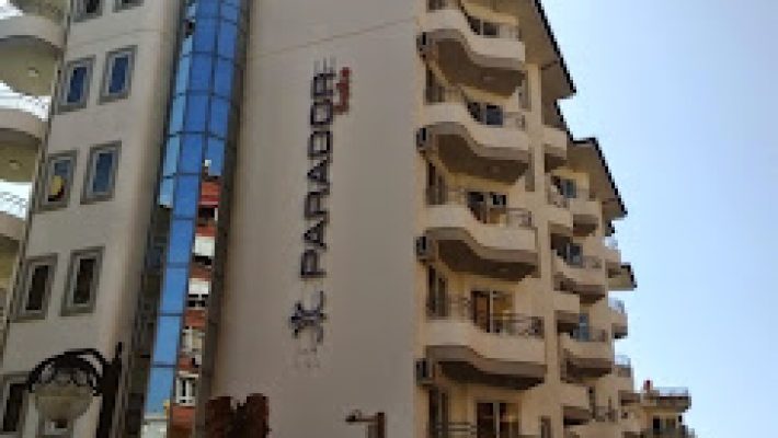 Parador Suite Apart Hotel’in açık yüzme havuzu, balkonlu apart odaları ve yeşil peyzajıyla çevrili alanlarıyla birlikte gündüz saatlerinde görüntülenmiş