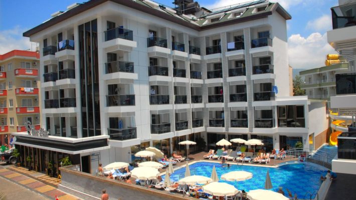 Alanya’daki Oba Star Hotel & Spa’nın açık yüzme havuzu, modern mimarili otel binası ve güneşlenme alanı.