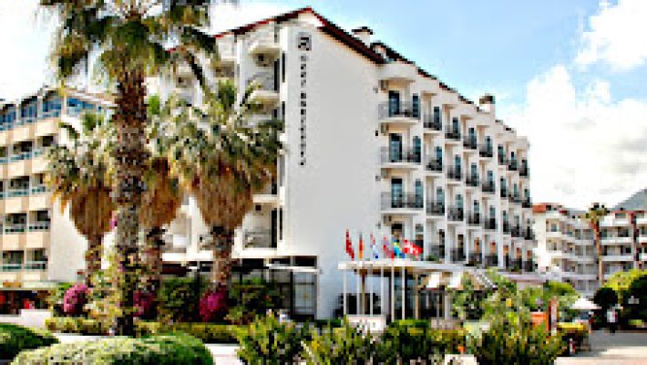 Otel Boulevard Alanya’nın palmiye ağaçlarıyla çevrili dış cephesi ve açık yüzme havuzu