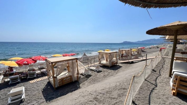 "Alanya sahilinde, gün batımında 66 Beach Bar Restaurant’ın denize sıfır masaları ve palmiyelerle çevrili oturma alanı"