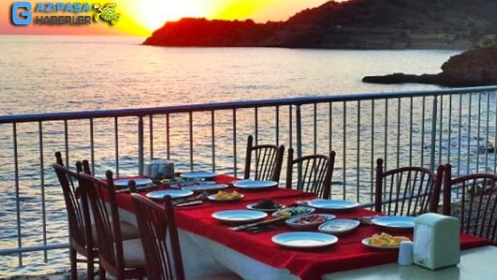 Giritli Balık Evi'nde deniz manzaralı masada servis edilen ızgara levrek, mezeler ve zeytinyağlılar. alanya