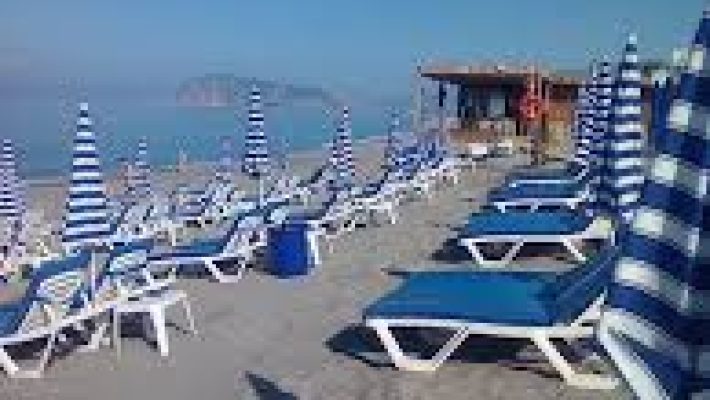 Blue Beach No:41 Alanya'nın turkuaz deniz manzaralı şezlongları, palmiye gölgeleri ve sahil kenarındaki modern beach bar alanı.