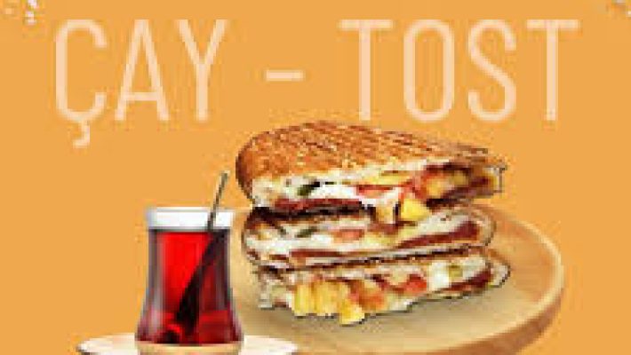 Tostu Ala Alanya’da servis edilen bazlamalı, bol kaşarlı ve sucuklu tost; yanında çıtır patates kızartması ve ayran ile birlikte sıcak tabak sunumu