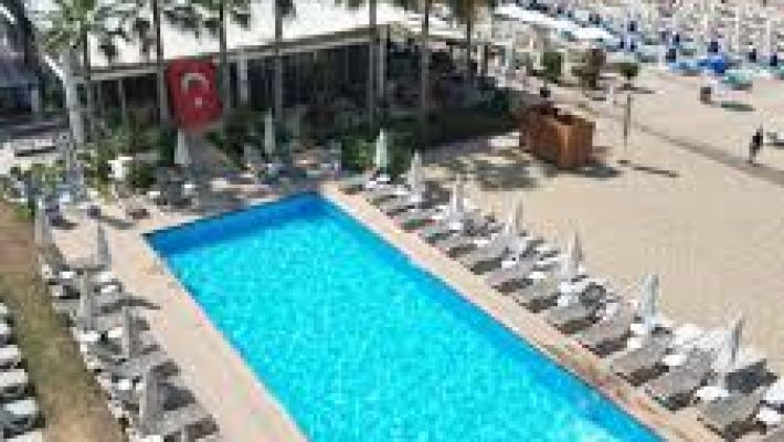 LOCO Beach Club Alanya’da palmiyelerle çevrili havuz başı alanı ve deniz manzaralı lüks şezlonglar