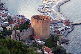 “Kızılkule ve çevresindeki tarihi yapılar, farklı medeniyetlerin izlerini taşıyan panoramik Alanya manzarası.”