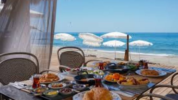 Alanya’da denize sıfır konumda yer alan Rest in Beach Plaj №54'te şezlonglar, güneş şemsiyeleri ve masmavi Akdeniz manzarası