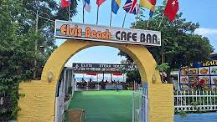 Alanya Elvis Beach Cafe Bar’da deniz manzaralı açık hava oturma alanı, masalar ve misafirler.