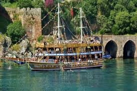 Piratenboot fährt entlang der Küste von Alanya bei Sonnenuntergang mit Gästen an Bord, 2026 Tourpreise angezeigt