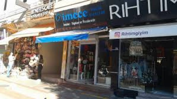 "İmece Müzik Aletleri mağazasında çeşitli enstrümanlar sergilenmiş, müşteriler ve öğrenciler ürünleri inceleyip çalıyor, modern ve düzenli bir müzik mağazası ortamı."