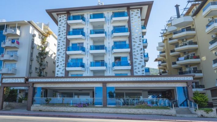 “Kleopatra Life Hotel’in plaja birkaç adım mesafedeki cephesi, balkonlu odaları ve açık yüzme havuzu.”