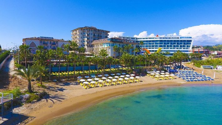 Alanya’da denize sıfır konumda yer alan Land Of Paradise Beach Hotel’in havuz başı ve modern bina görüntüsü