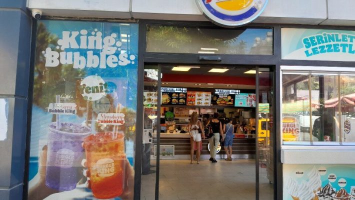 Burger King Alanya’da Whopper menü sunumu; közlenmiş burger köftesi, patates kızartması ve buz gibi kola ile tepsi üzerinde hızlı servis sunumu