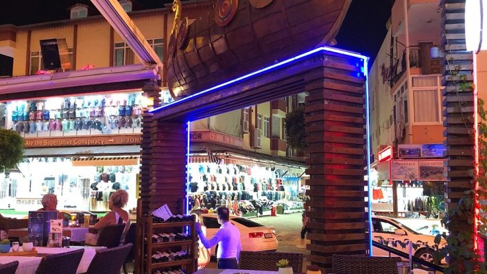 Melani Restaurant Alanya’da kaya dekorlu açık alanda ızgara et, makarna tabakları, nargile ve akşam yemeği sofrası.