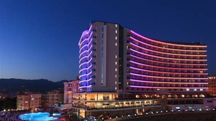 Diamond Resort SPA Hotel Alanya’nın palmiyelerle çevrili havuzu ve modern mimariye sahip otel binası.
