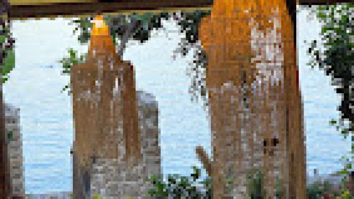 Tersane Cafe’nin tarihi Alanya Tersanesi manzaralı açık oturma alanı, denize karşı servis edilen kahve ve tatlılarla birlikte gün batımında görüntülenmiş