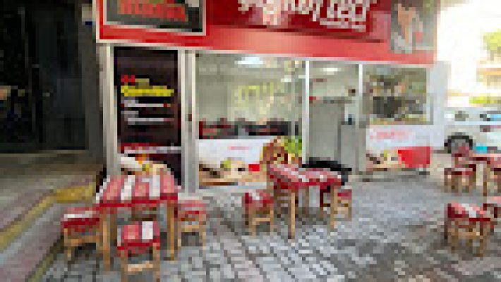 Çiğköfteci Mahmut Usta’da bol yeşillikli, limon dilimli ve nar ekşili Adıyaman usulü çiğ köfte dürüm servisi; yanında ayran ile birlikte masada sunulmuş